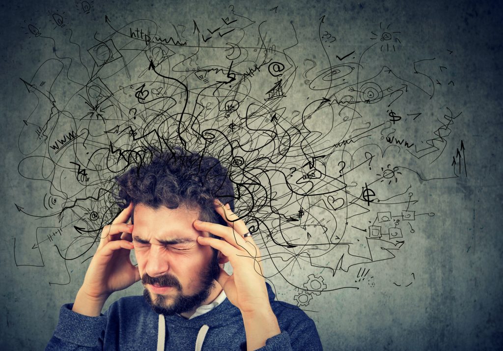 Pained, stressed young man with a tangled thoughts coming out of his head