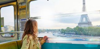 Beautiful young woman travelling in a train of Parisian underground and looking through the window at the Eiffel tower